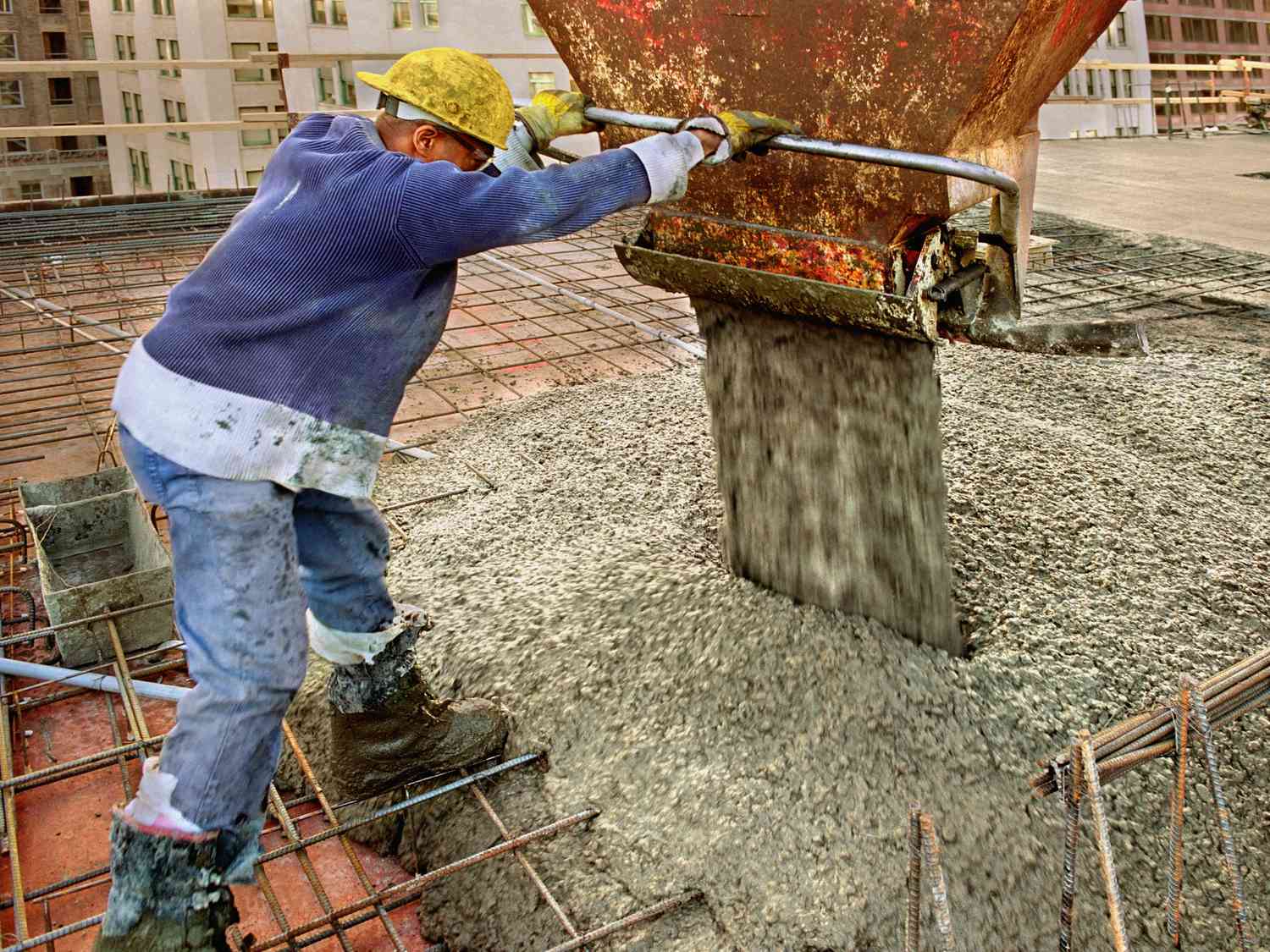 Trabalhador da construção civil despejando concreto