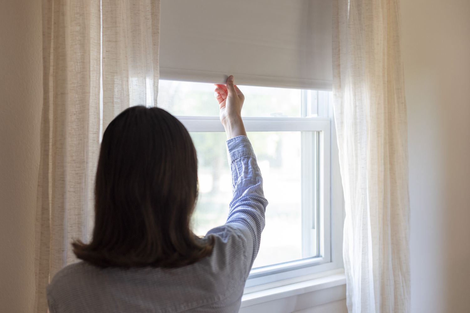 Persianas sendo baixadas para diminuir a conta de luz