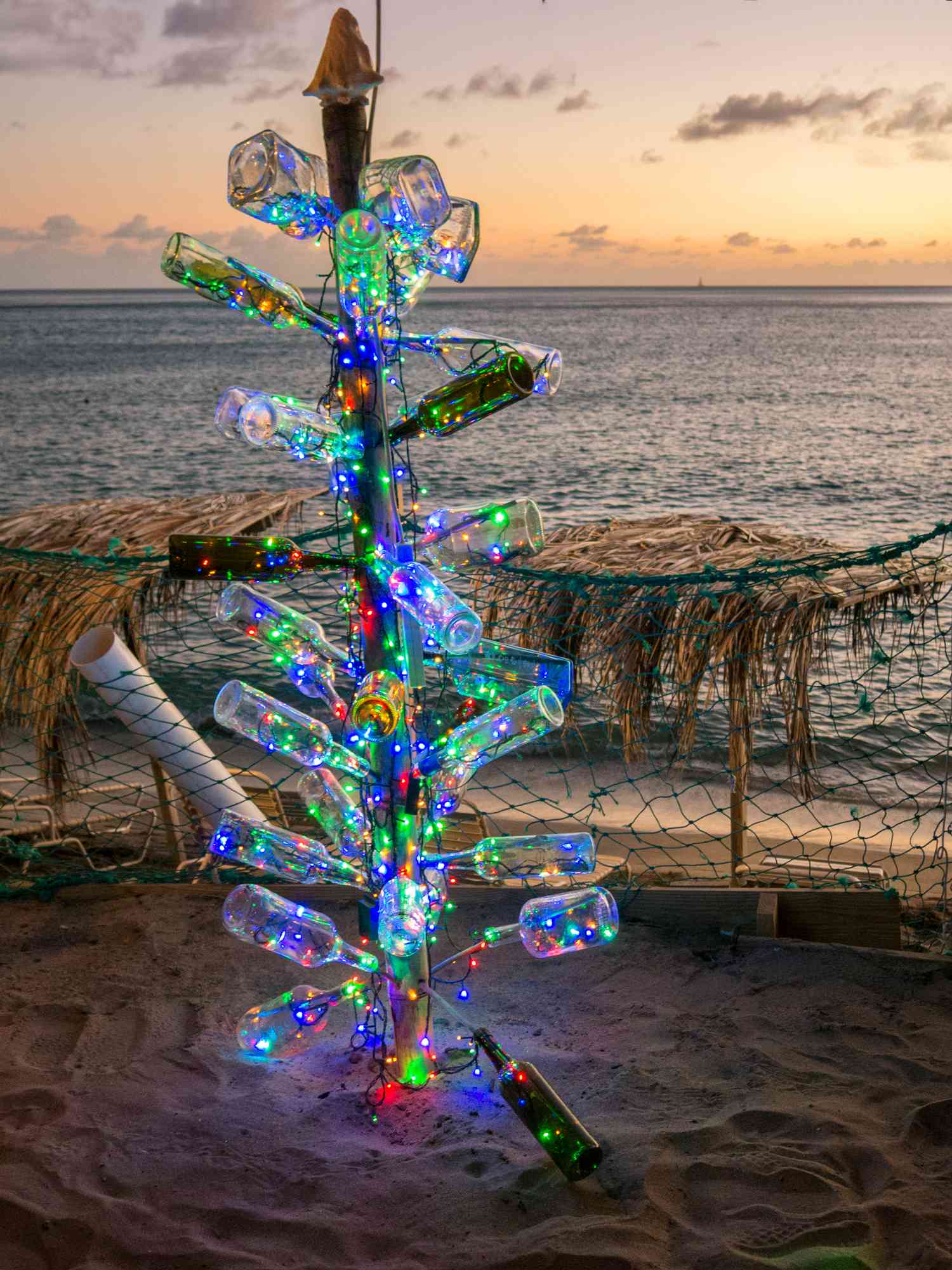 Weihnachtsbaum am Strand aus Flaschen mit Lichtern darin 