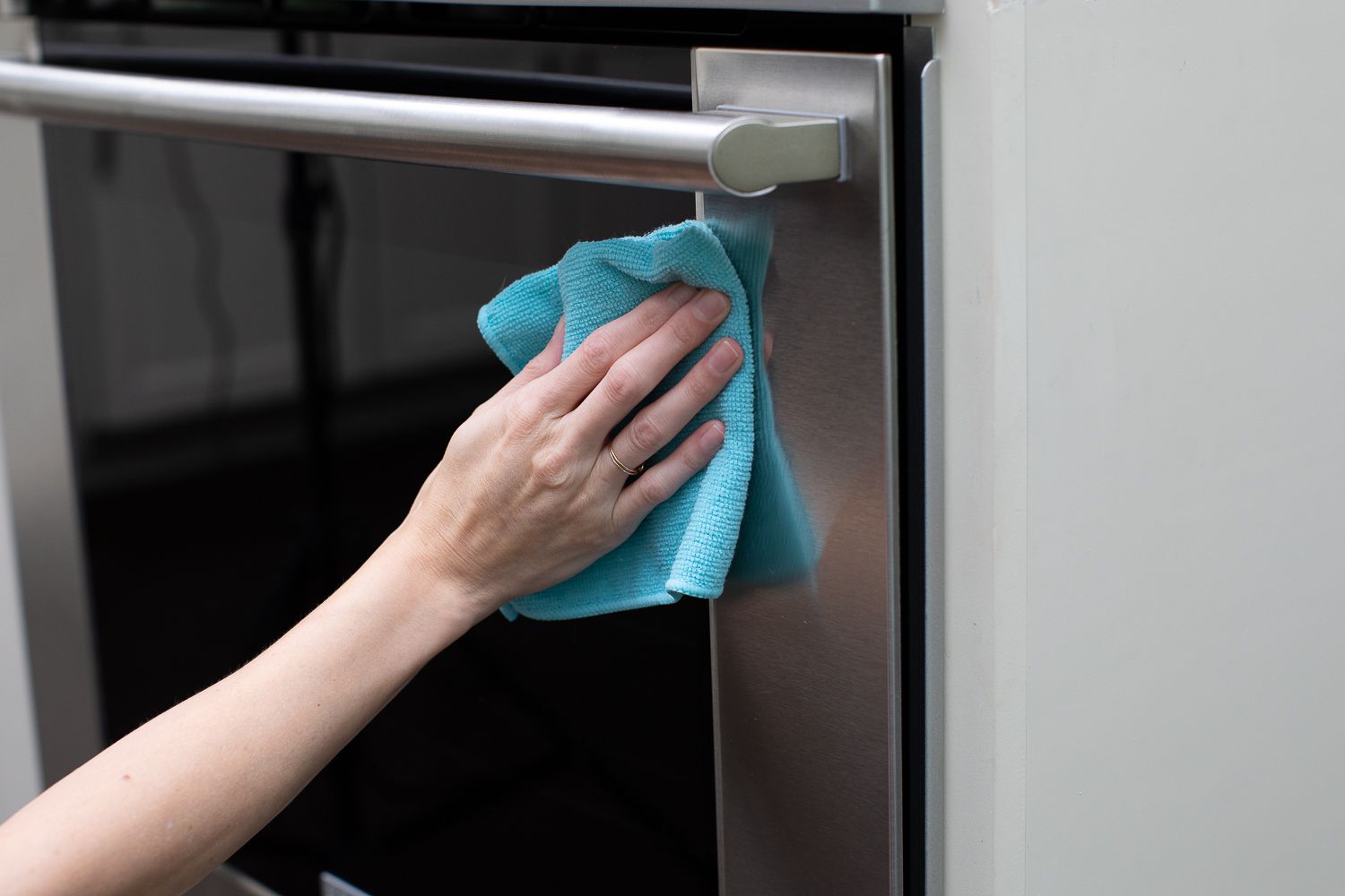 Exterior de la puerta del horno limpiado con un paño de microfibra azul