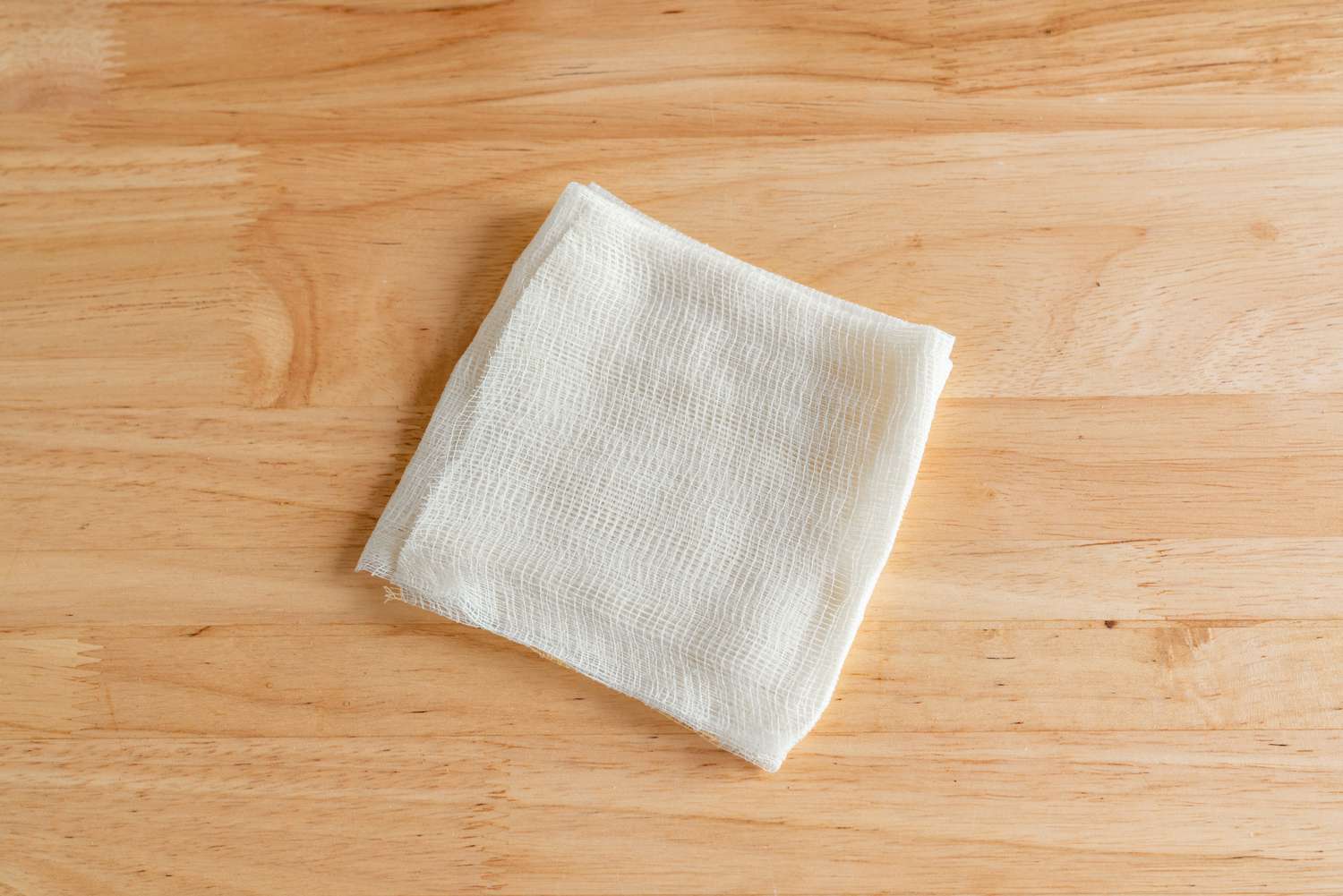 Toalha de prato de algodão branco dobrada sobre superfície de madeira
