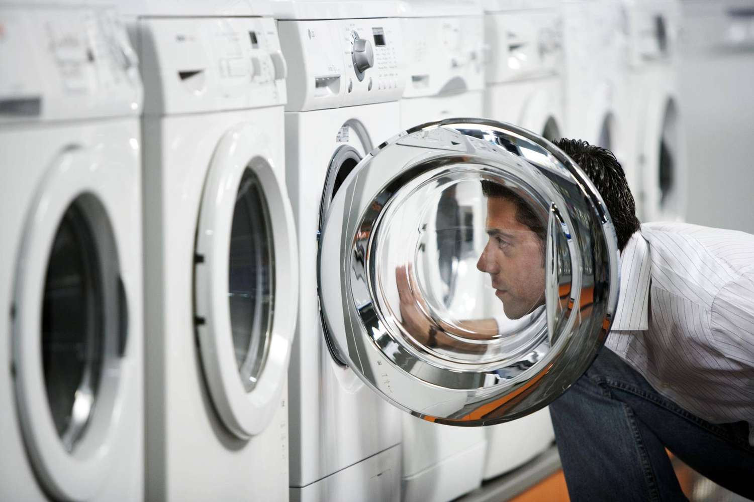 Mann inspiziert Waschmaschine im Geschäft