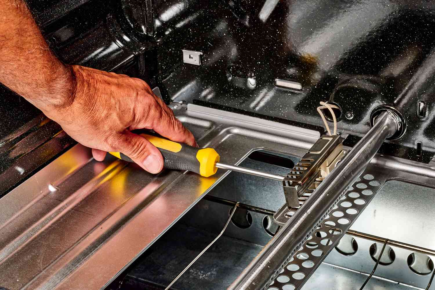 Screwdriver loosening gas oven ignitor for removal