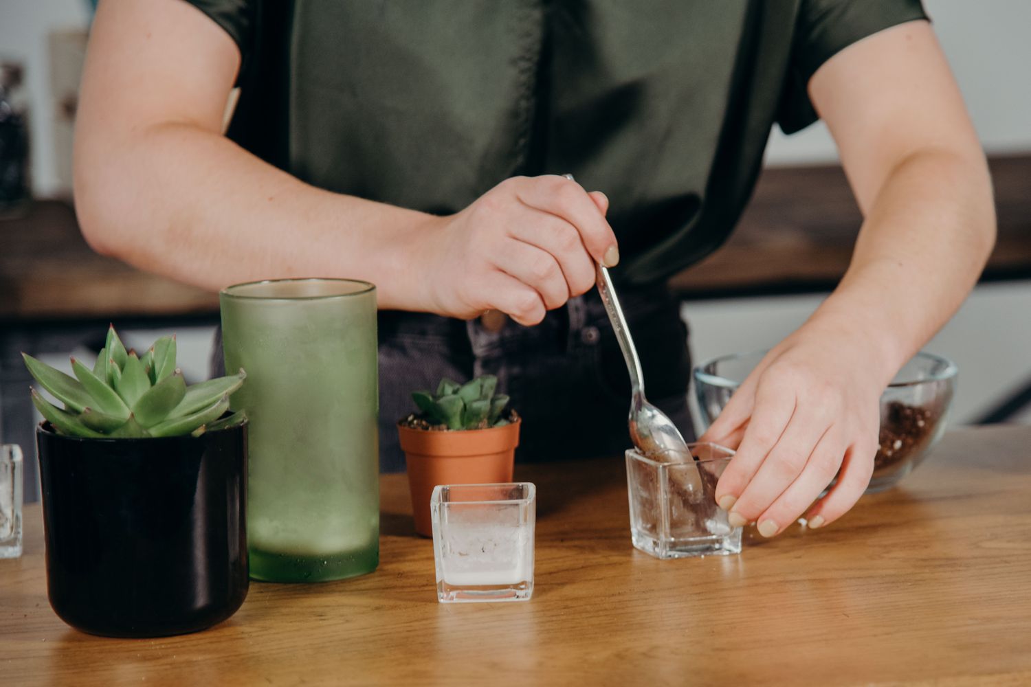 Woman putting soil into an empty candle votive