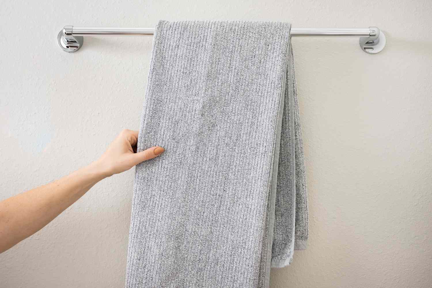 Serviette gris clair pliée et drapée sur le porte-serviettes de la salle de bain