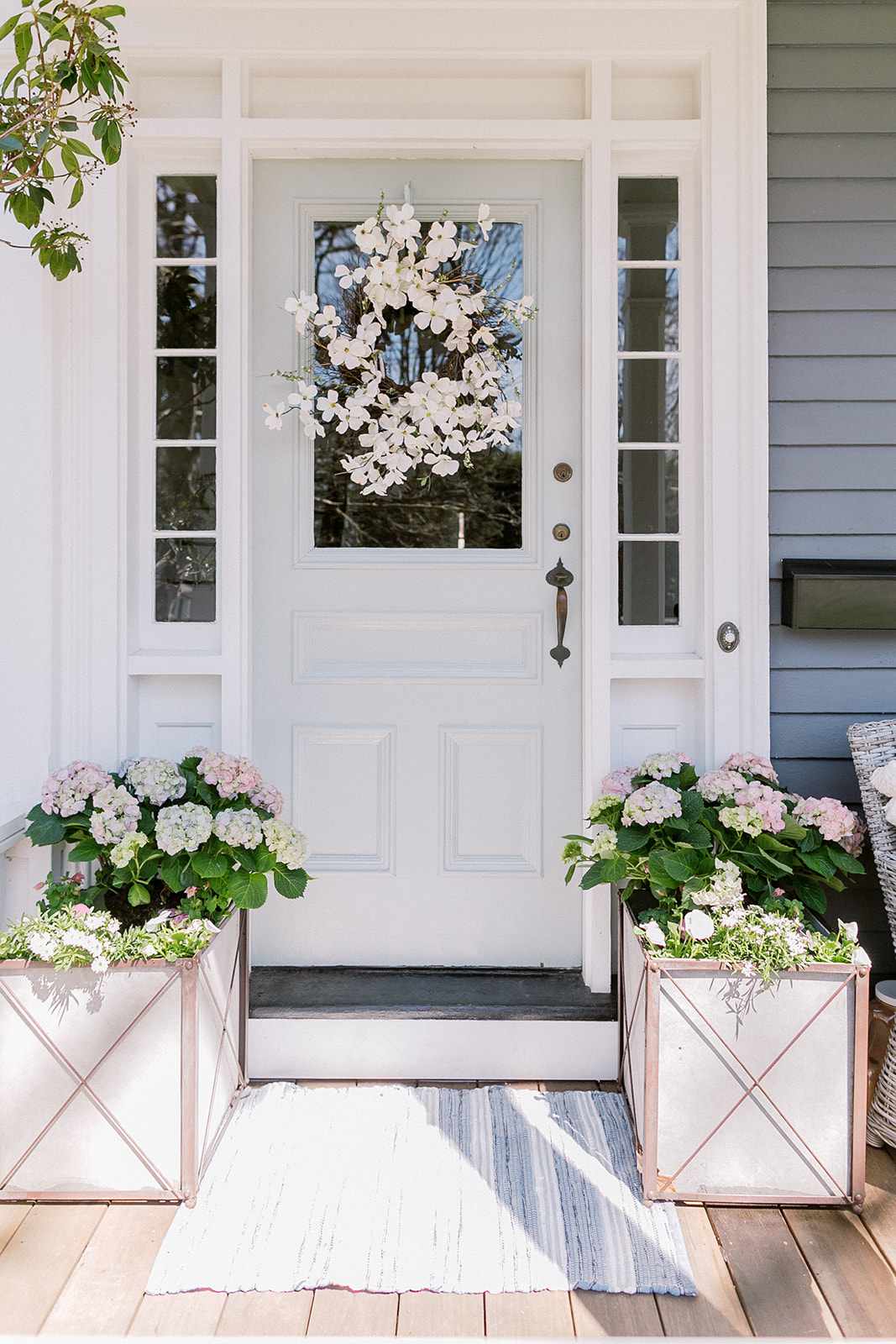 Eine mit Blumen geschmückte Haustür in hellem Salbei.
