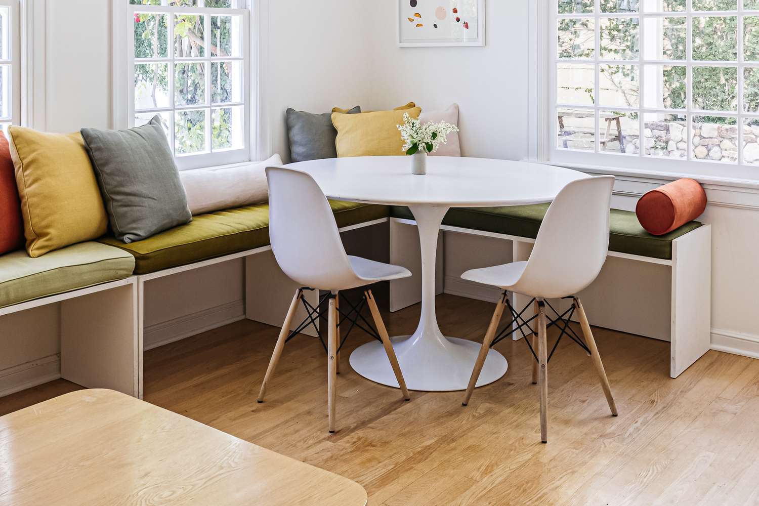 Weißer Saarinen-Tisch mit zwei Stühlen und Fensterecke mit Bänken