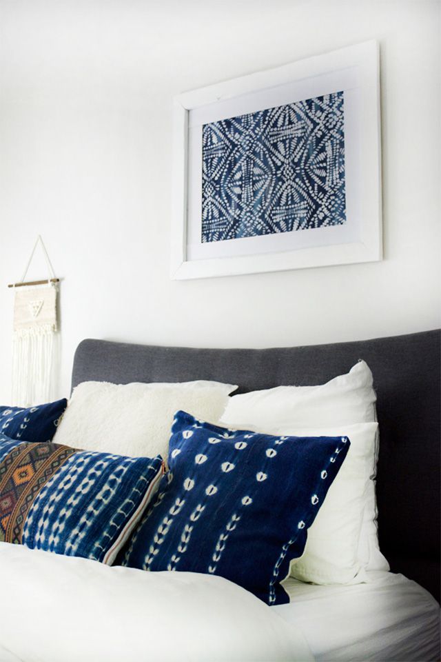 Uma cama com uma obra de arte com estêncil azul acima dela