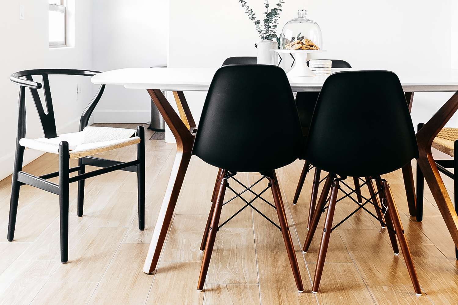 Black Eames molded side chairs surrounding white dining table