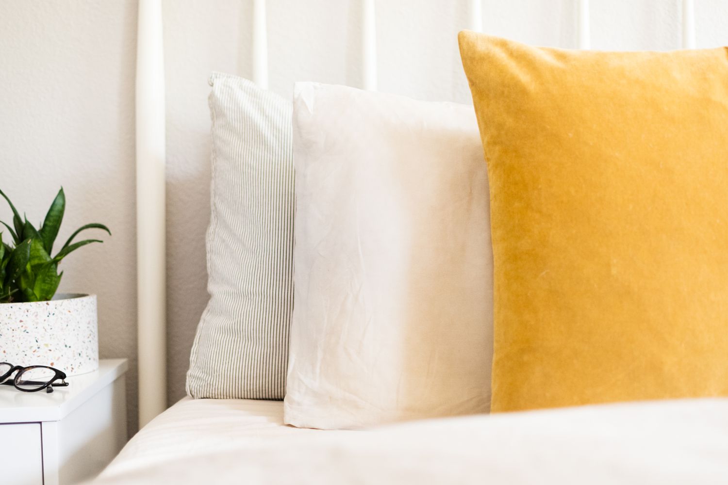Weiße und gelbe Kissen auf dem Bett in Großaufnahme