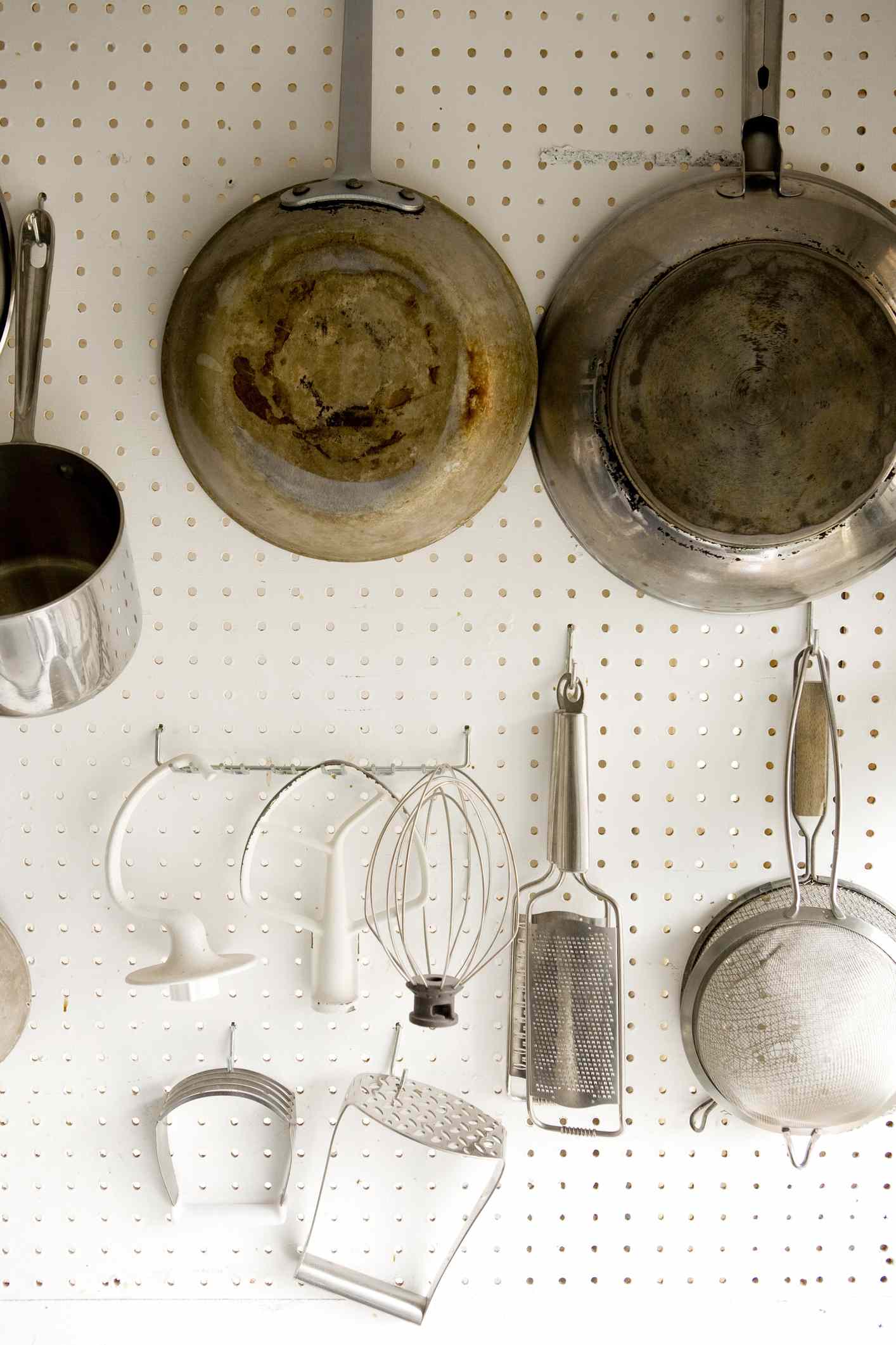 Panelas e outros utensílios de cozinha pendurados em um quadro branco