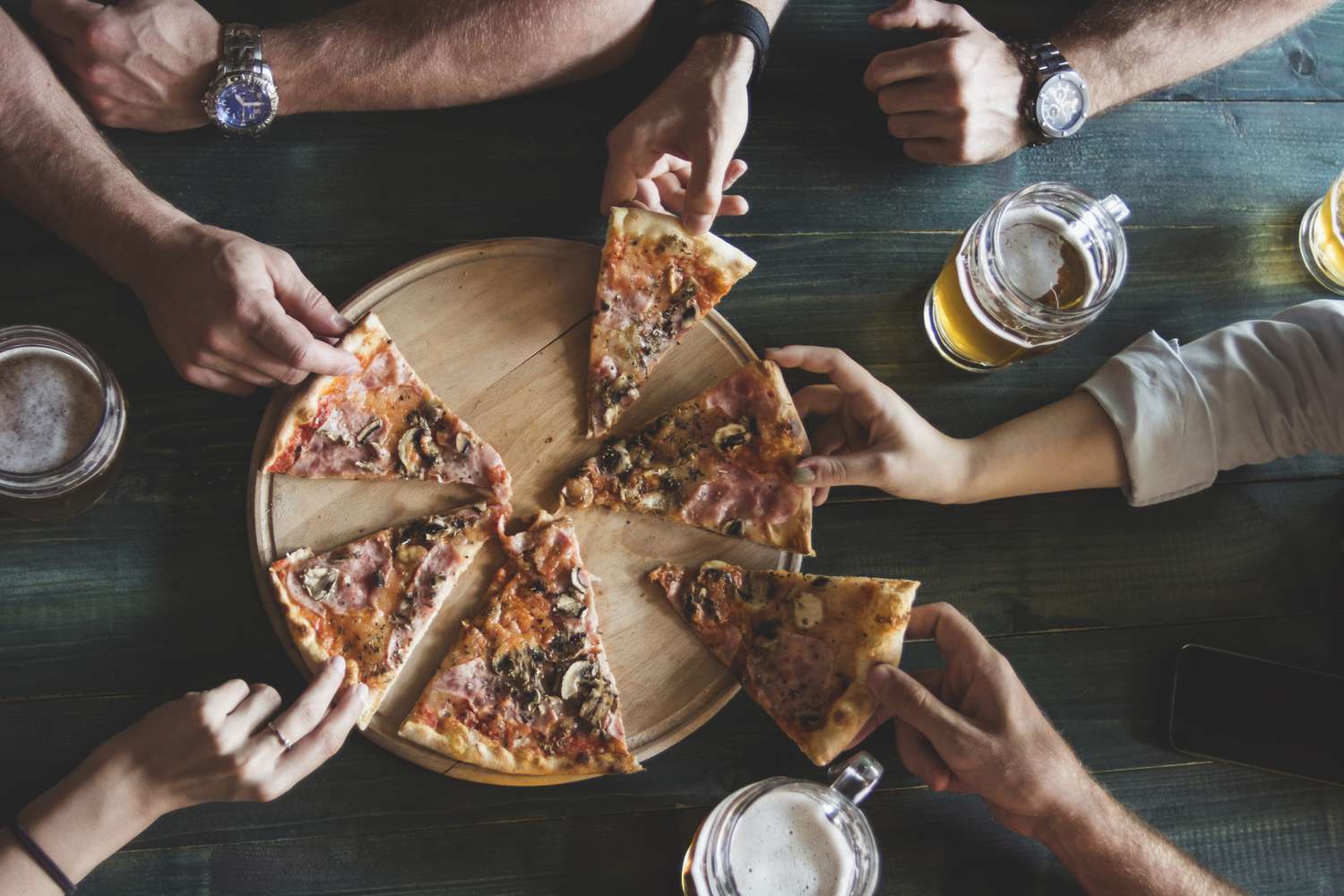 Eine Übersichtsaufnahme von Freunden, die Bier trinken und Pizza essen.