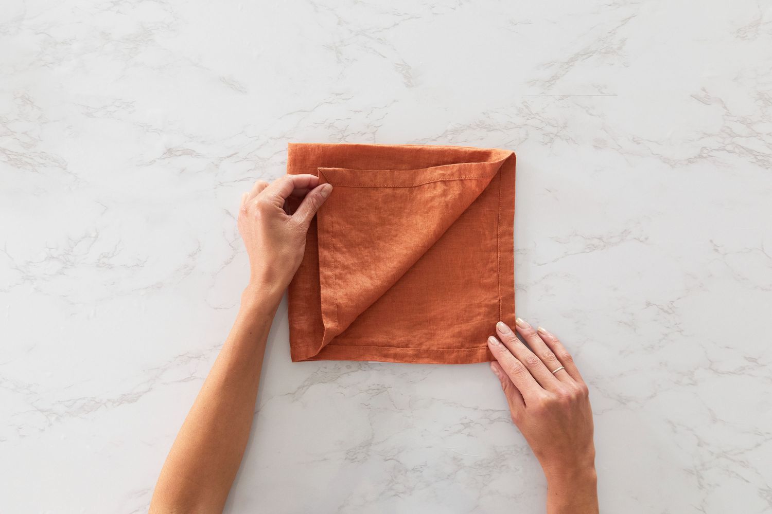 Orange cloth napkin folded in half corner pulled back diagonally