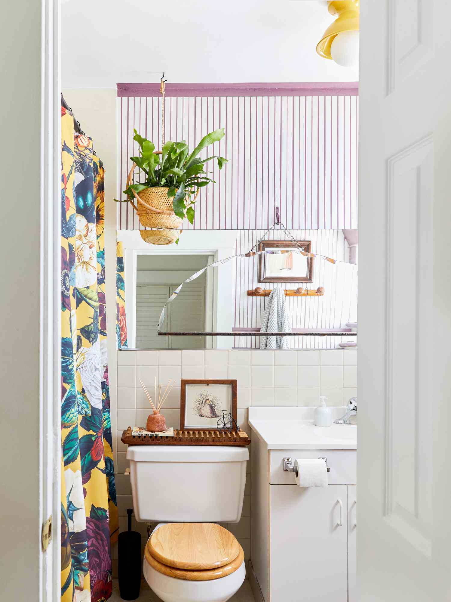 Lila akzentuiertes Badezimmer mit Toilettenpapierhalter auf dem Waschtischunterschrank