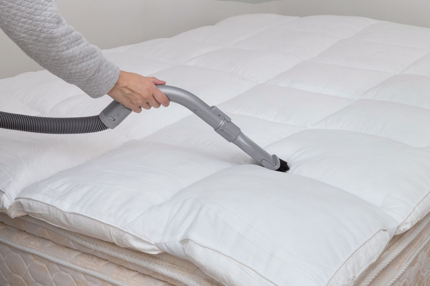 Mattress topper cleaned with vacuum hose and brush attachment