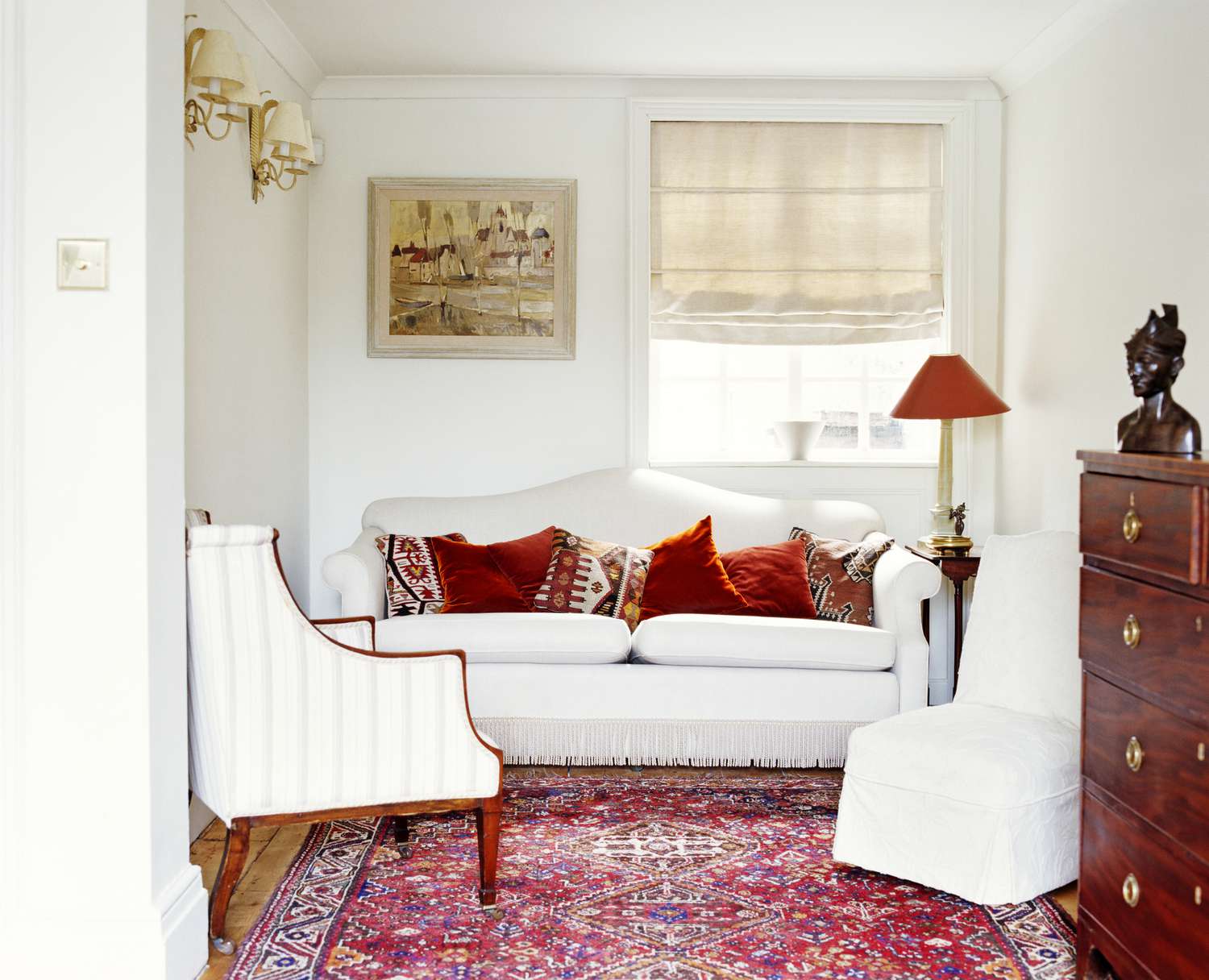 red area rug anchoring a living room with white furniture