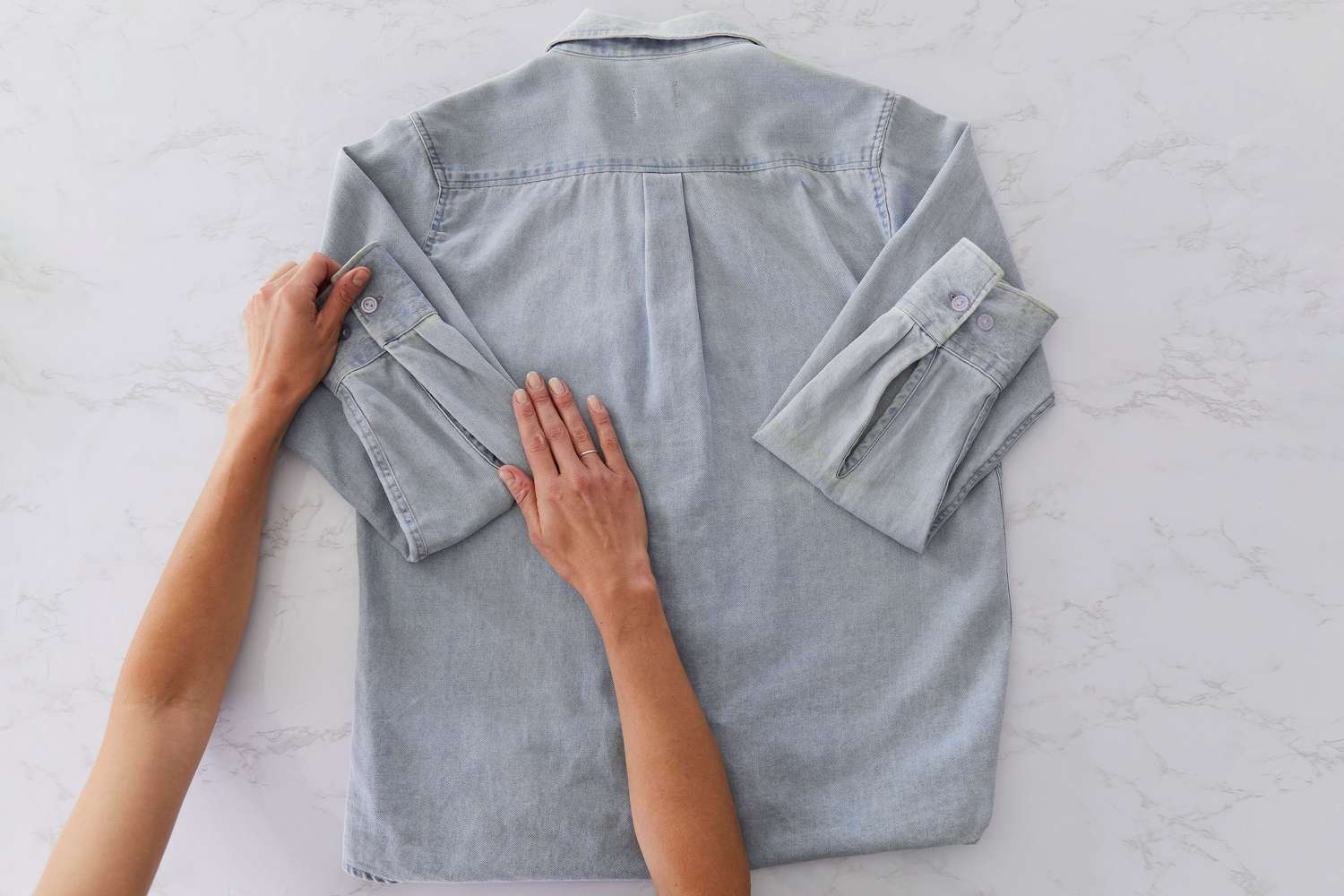 Camisa jeans cinza com botões e mangas dobradas do punho ao ombro