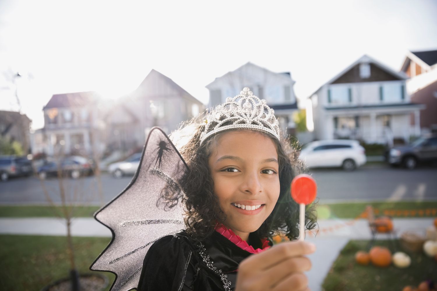 Mädchen im Halloween-Kostüm hält einen Lutscher hoch