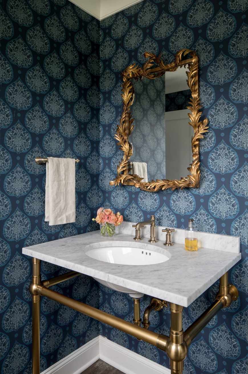 banheiro com papel de parede de padrão azul e espelho ornamentado dourado