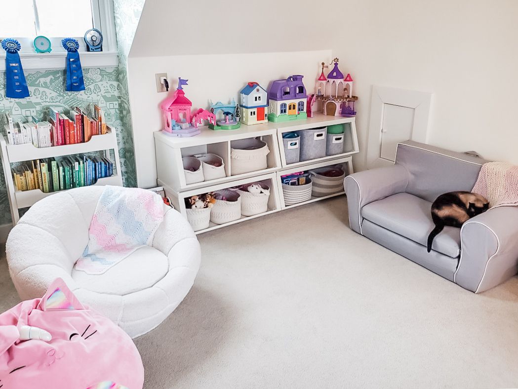 Zimmer mit schräger Decke und Regalen für Kinderspielzeug und Bücher