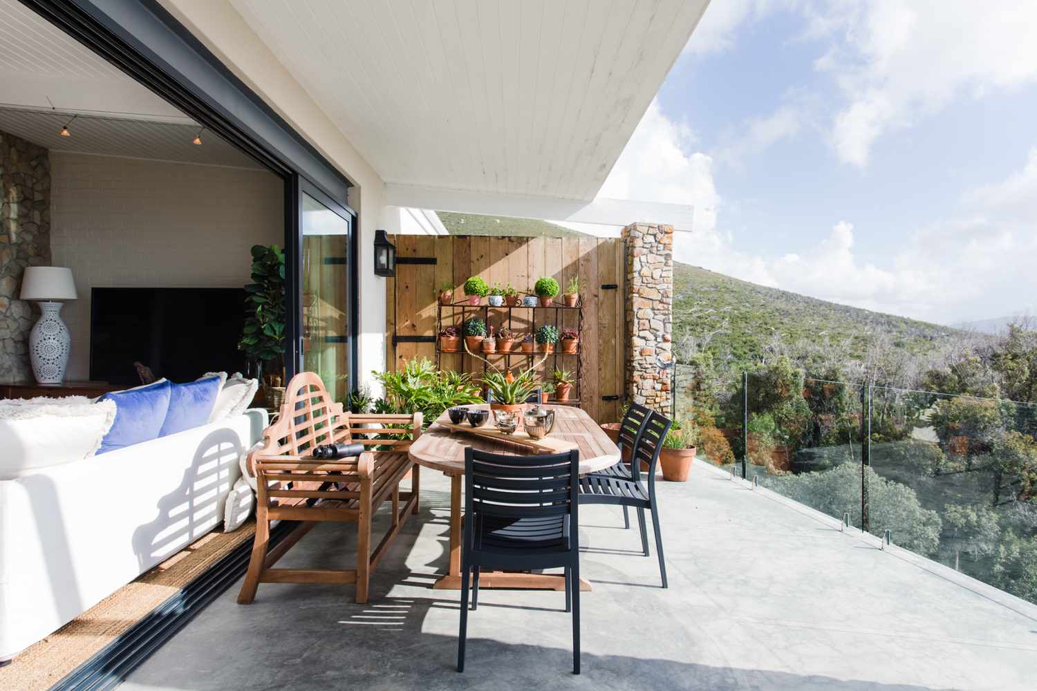 Open patio with outdoor dining table overlooking hill in sunlight