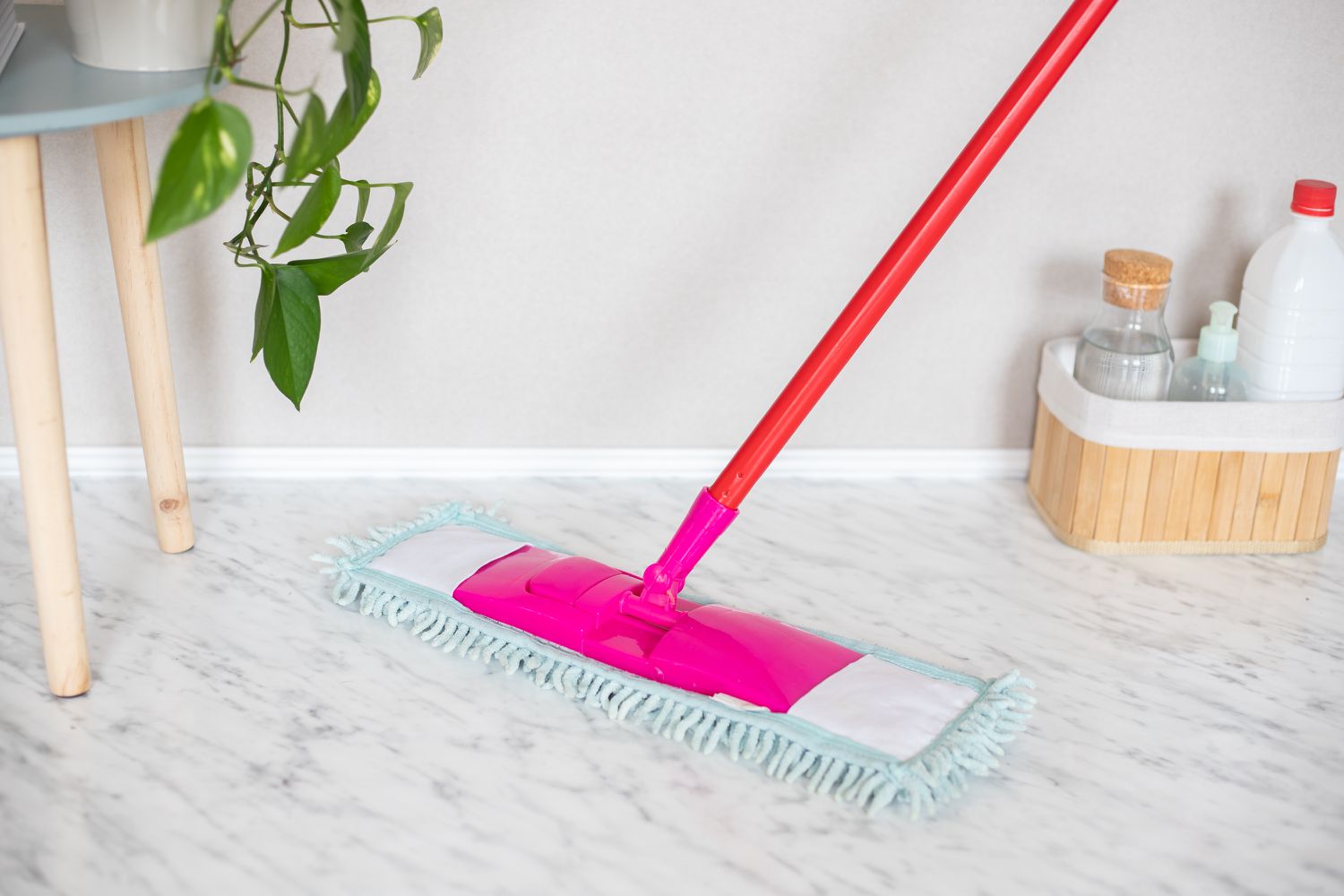 Dry mop passing over marble floor next to toiletries in basket