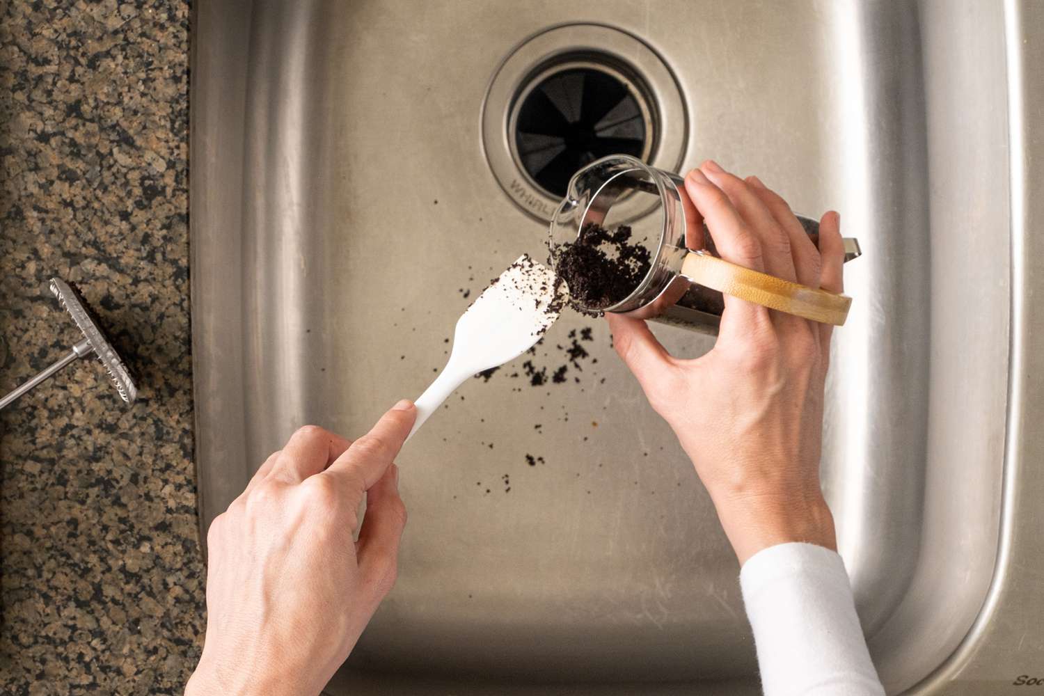 Coffee grounds disposed from french press in kitchen sink