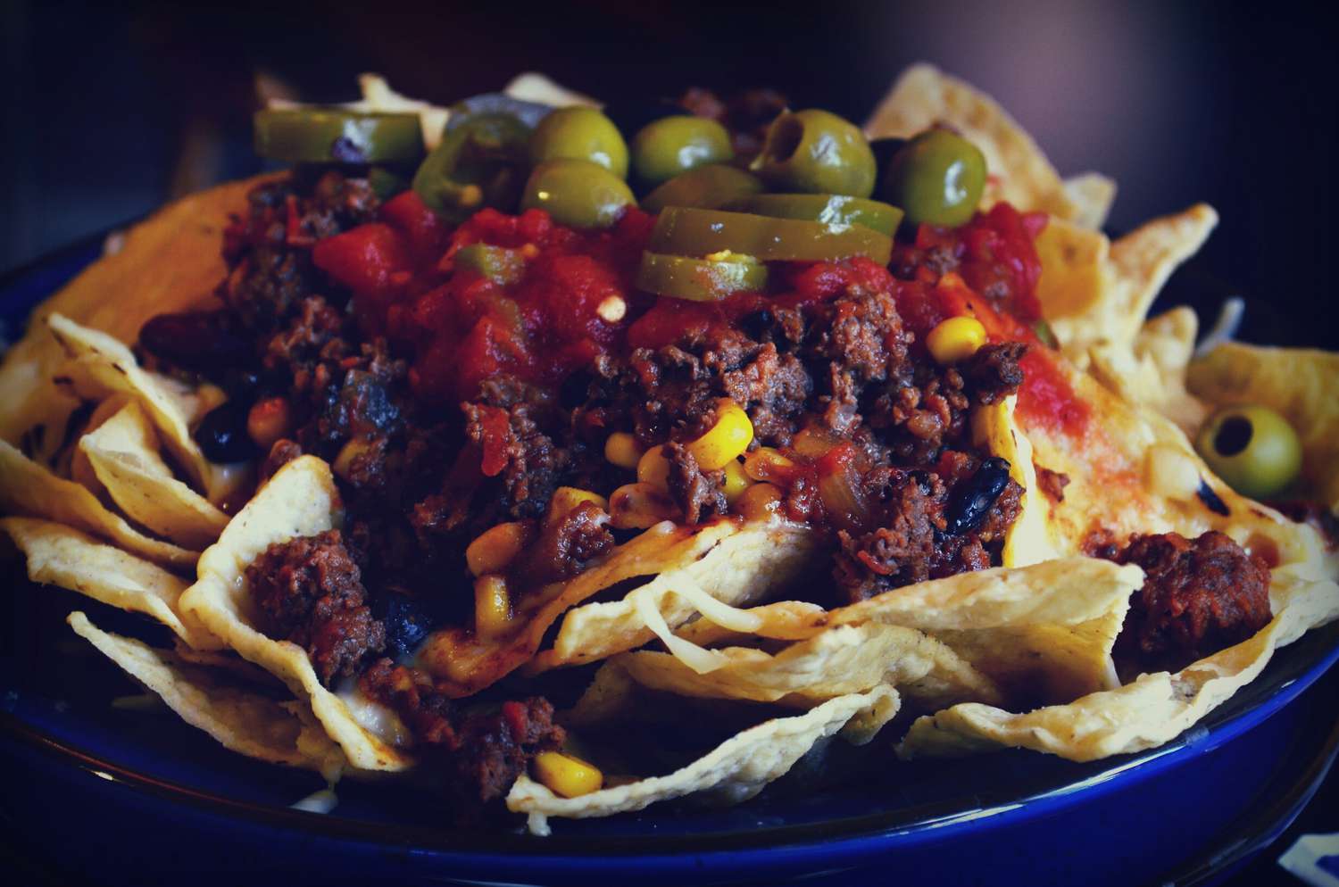 Nachos mit Fleisch, Oliven, Paprika und Tomaten.