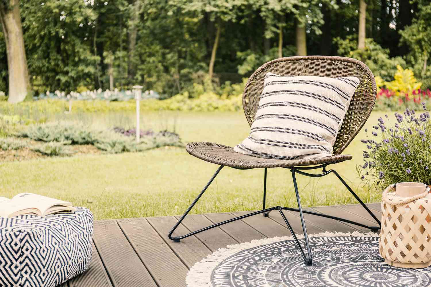 Echtes Foto eines modernen Gartenstuhls mit einem weißen, gestreiften Kissen auf einem Holzdeck im Garten eines Wochenendhauses