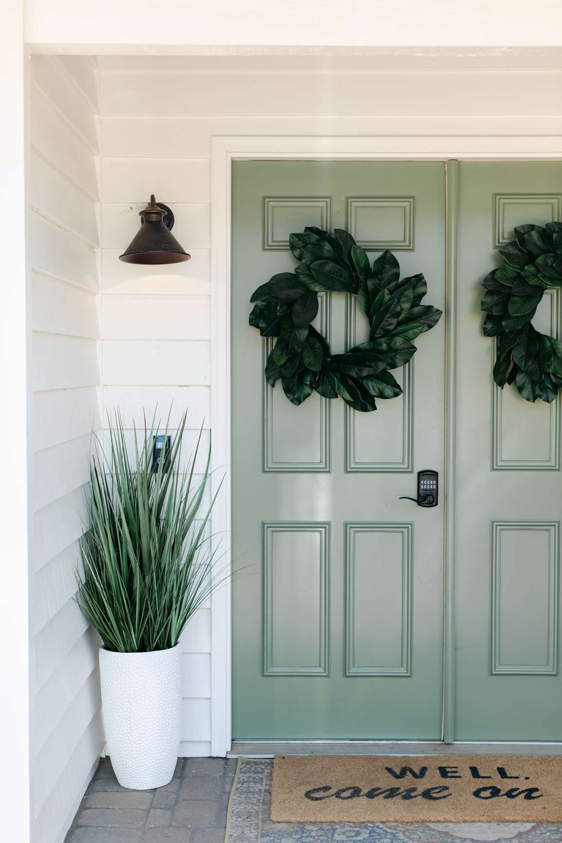 Eine grüne Haustür, geschmückt mit einem Magnolienblattkranz