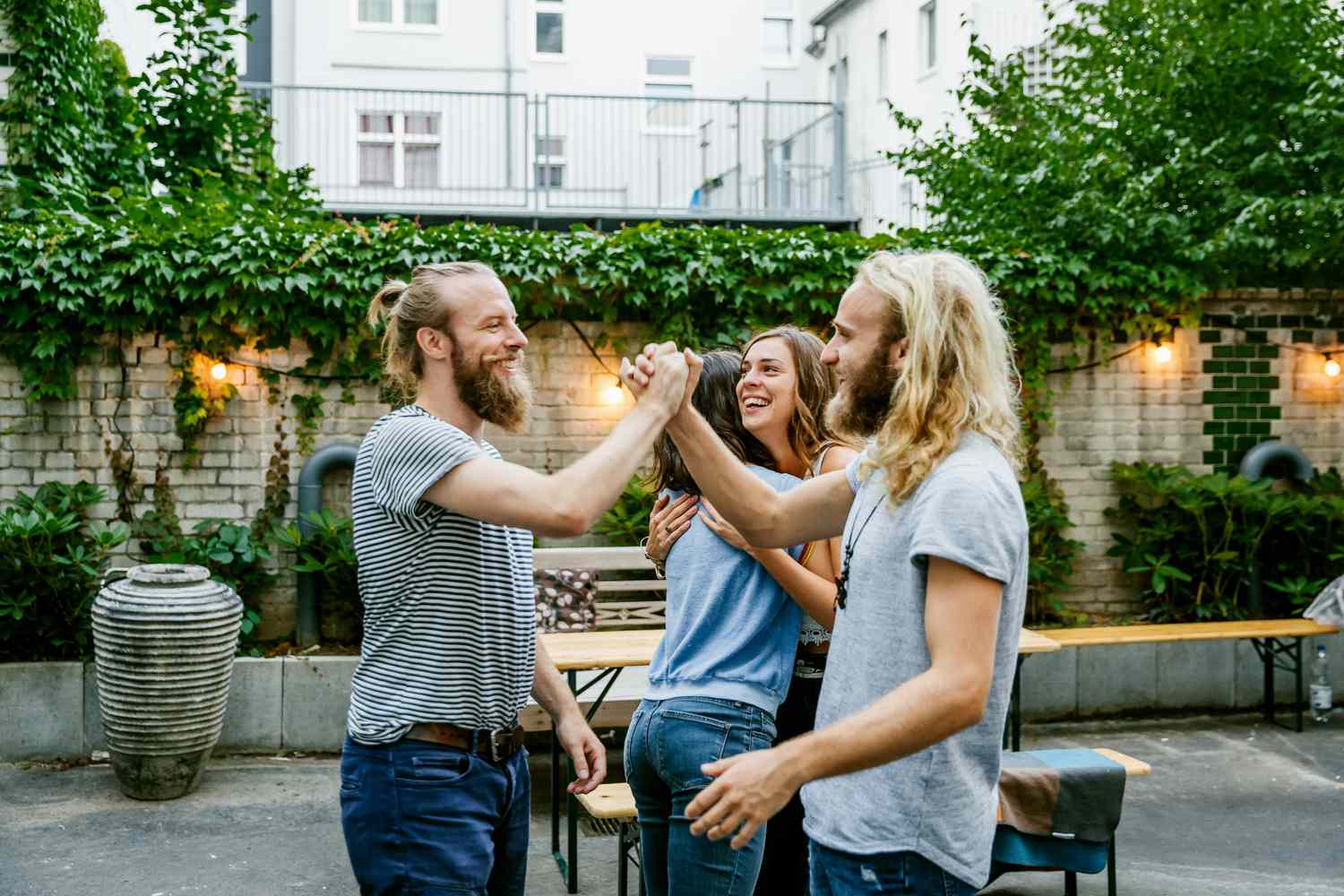 Zwei junge Kerle freuen sich, einander bei einem Grilltreffen mit Freunden zu sehen