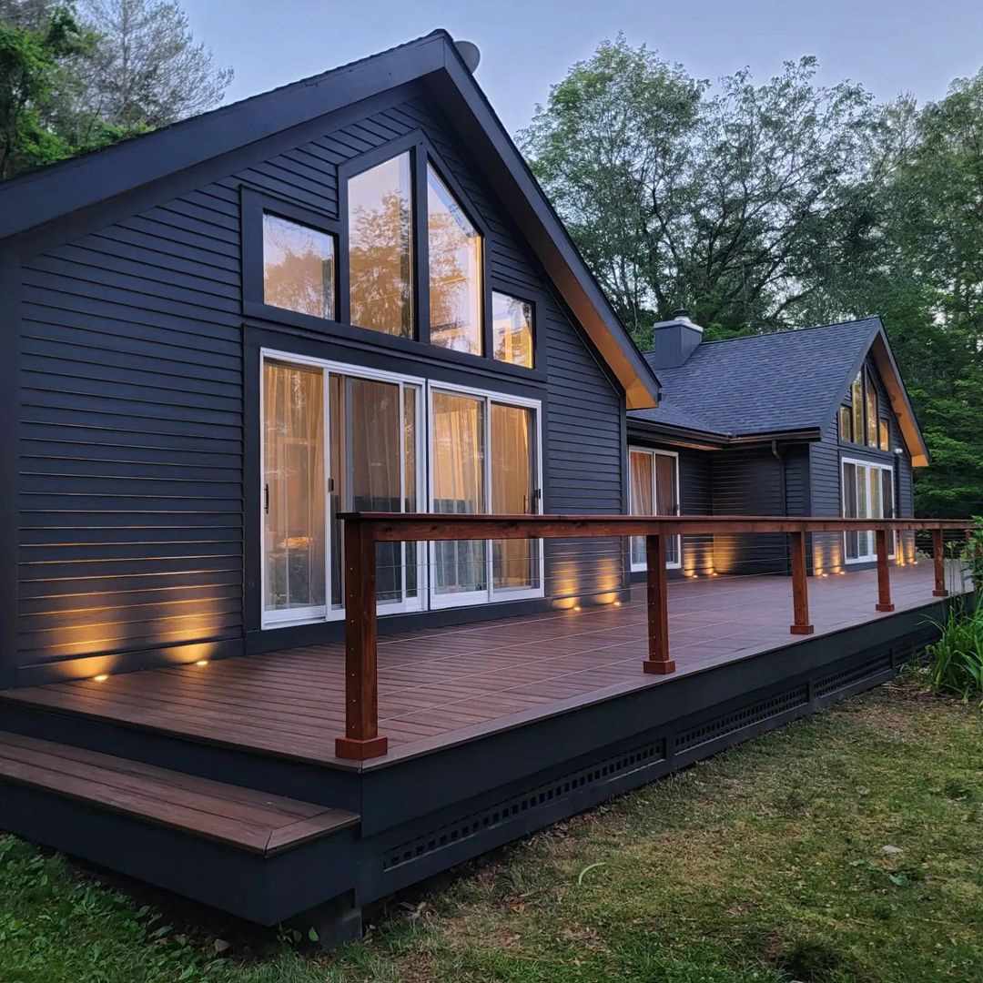 Ein Haus mit einem Holzdeck mit Geländer auf der Rückseite