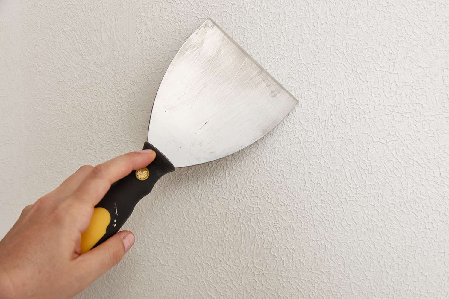 Use drywall knife to smooth out the textured surface
