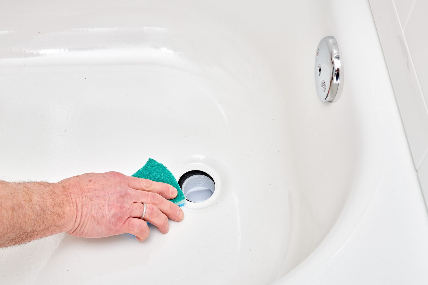 Non-scratch scouring pad removing putty from tub drain opening