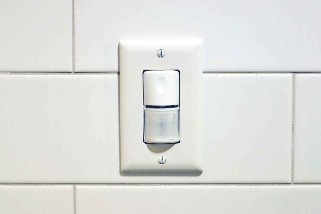 Uma foto em close de um interruptor de luz com sensor de movimento na parede