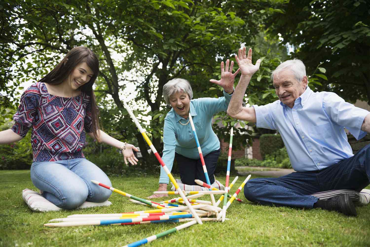Großeltern und Enkelin spielen mit riesigen Pick-up-Sticks