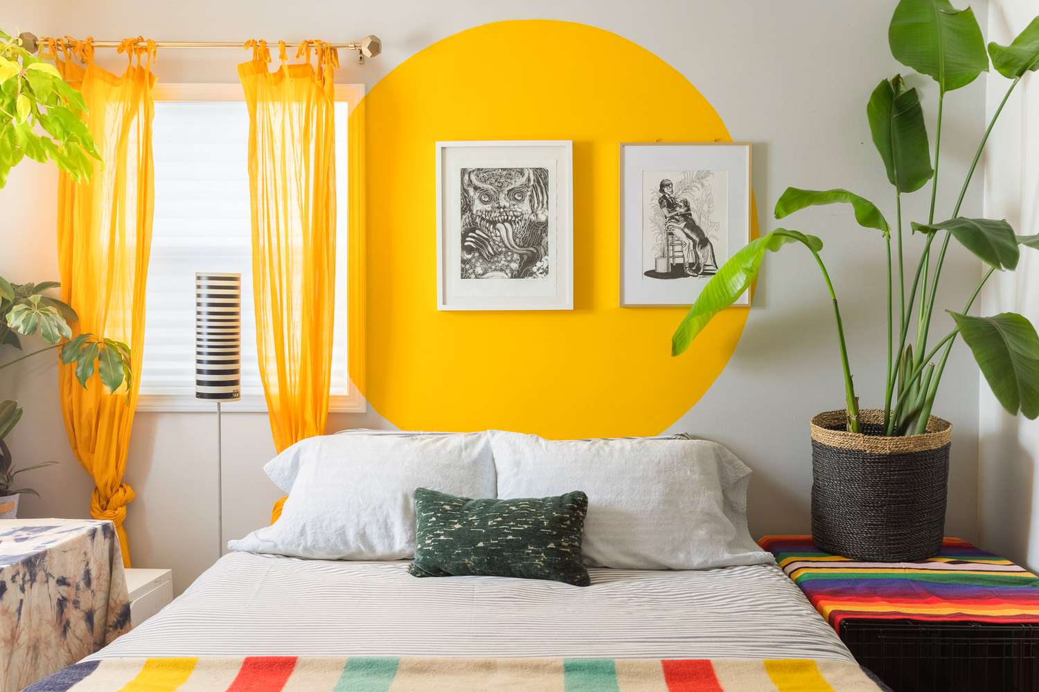 Dormitorio con un círculo amarillo brillante decorando la pared del fondo con dos obras de arte enmarcadas