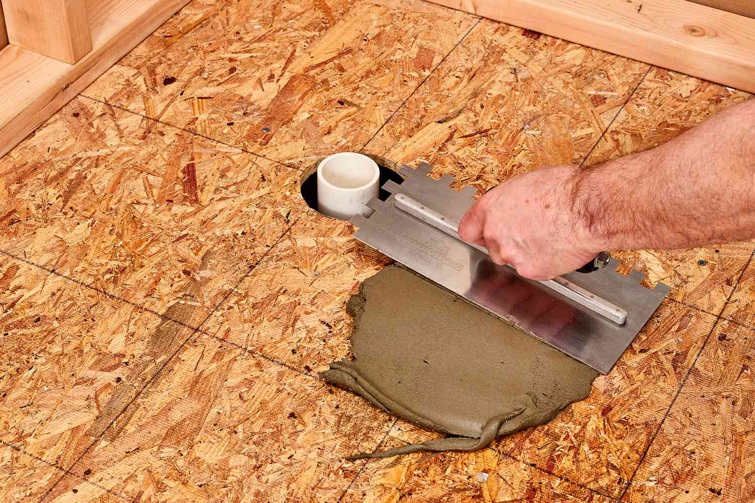 Mortar spread across plywood floor to create shower pan base