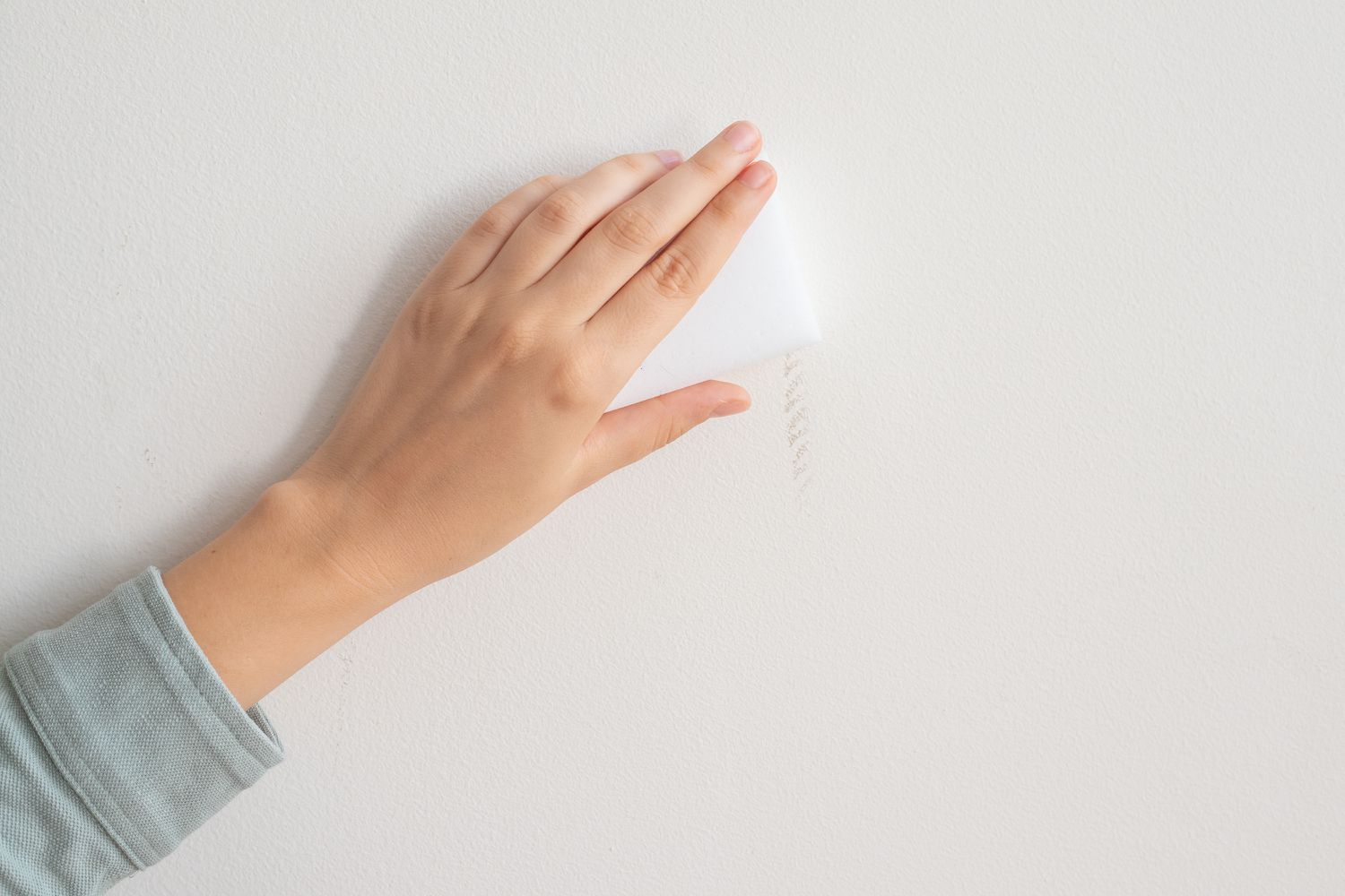 Magic eraser scrubbing white wall to remove scuff mark