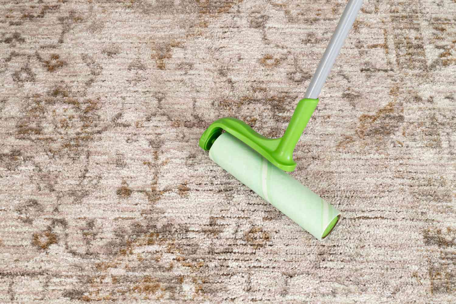 Person using a sticky roller to clean a rug