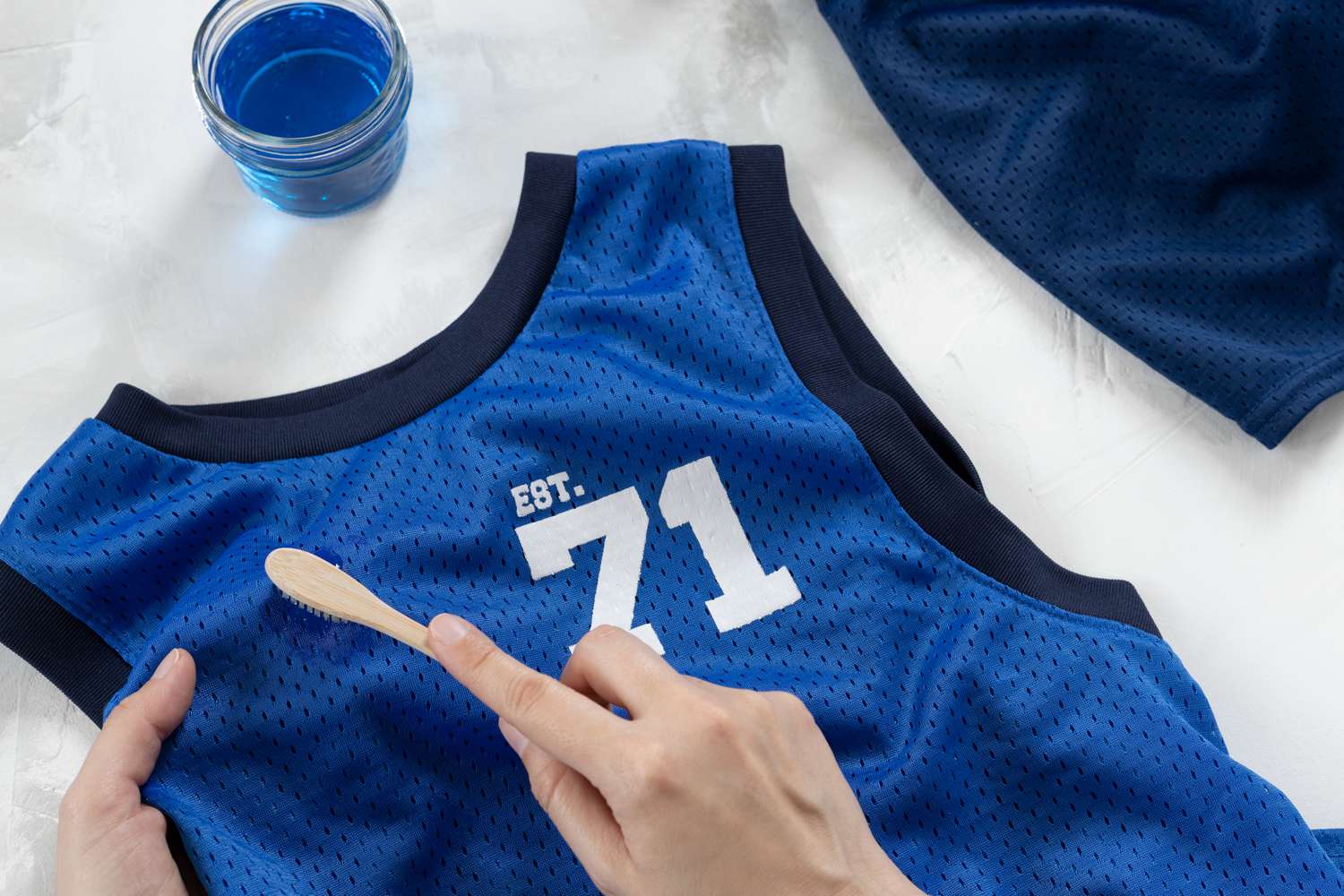 Blue basketball jersey scrubbed with old toothbrush and laundry detergent to treat blood stains