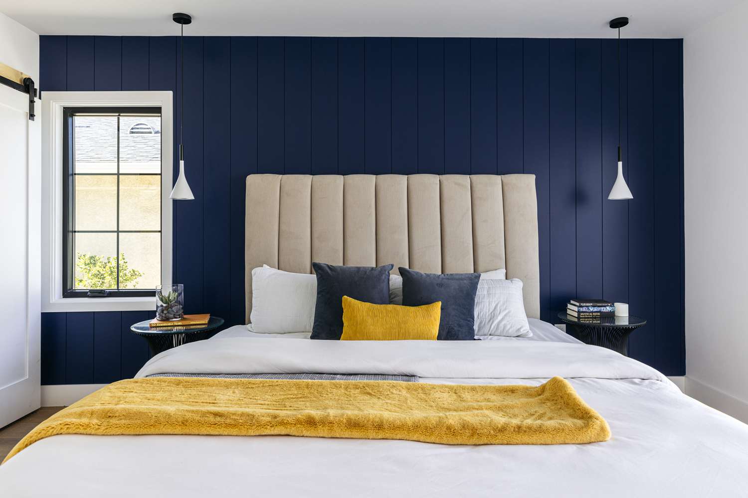 Parede de acento shiplap azul escuro e cobertor amarelo dobrado sobre a cama feita