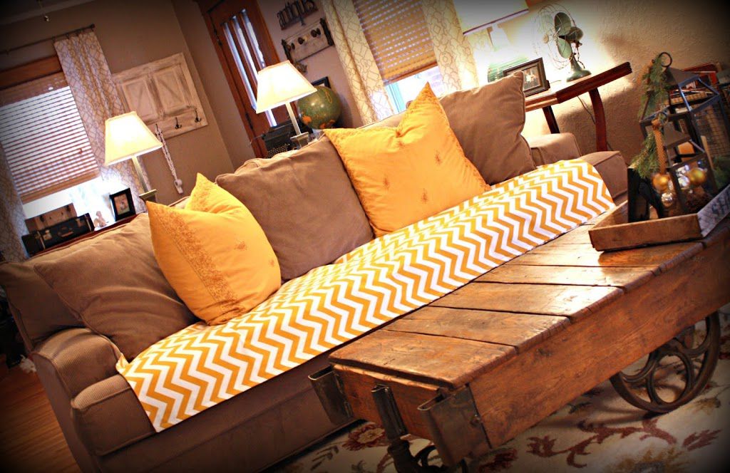 Un sofá de color tostado y amarillo con una funda de asiento de chevron.