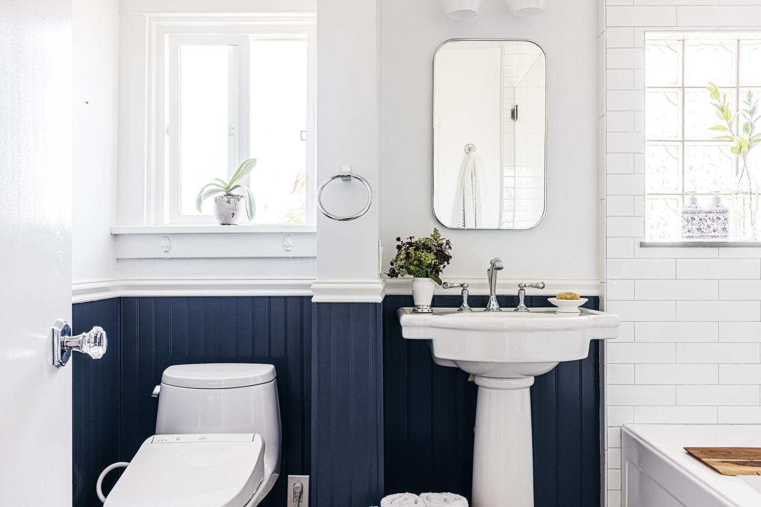 Banheiro pequeno com paredes brancas divididas com tratamento de beadboard azul-marinho