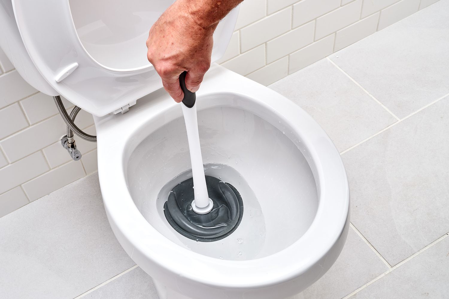 Toilet plunger pushed into bowl to loosen clog
