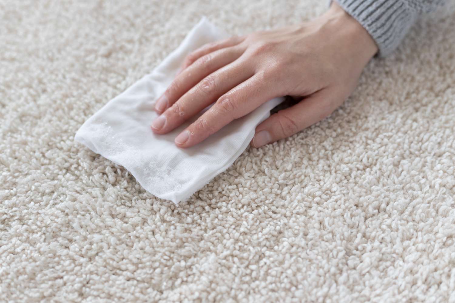 Weißes Papierhandtuch, das Teppich mit Ostereierfleck abtupft