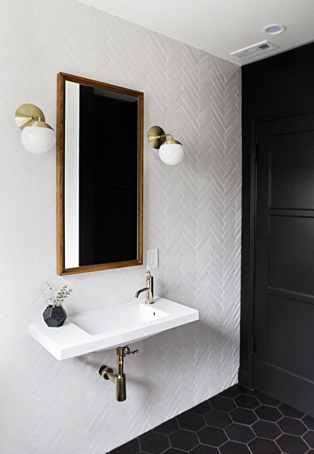 Banheiro preto e branco com parede de azulejos em espinha
