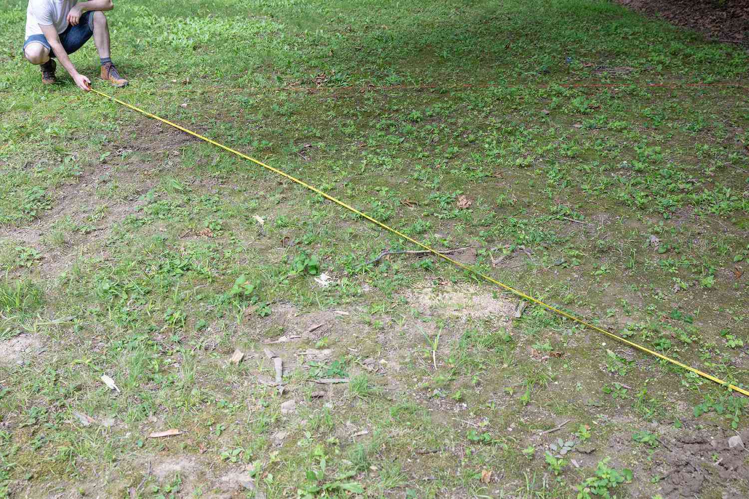Erbsenkiesumrandung wird auf dem Rasen mit gelber Schnur gemessen