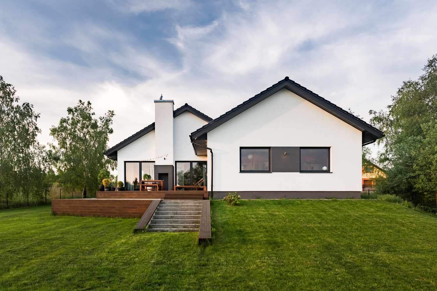 Maison blanche élégante avec jardin et terrasse sur une colline en pente