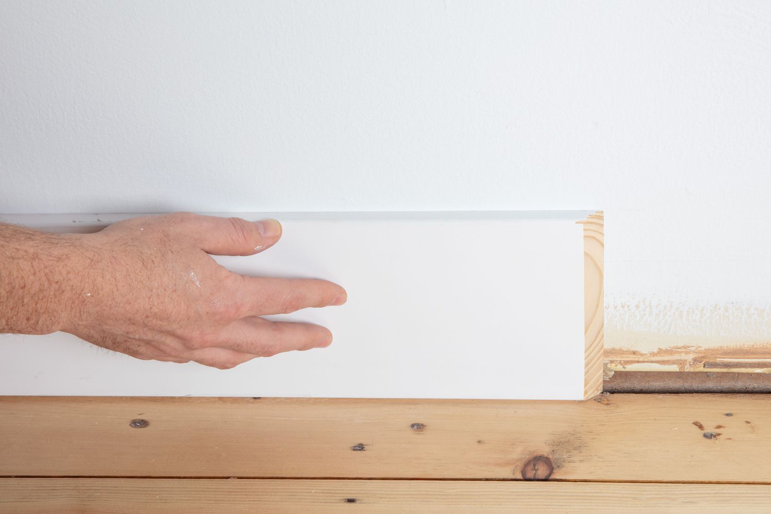 Toma de alguien alineando un rodapié contra la pared y el suelo